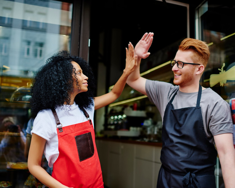 Two colleagues high-fiving to celebrate achievement at work.